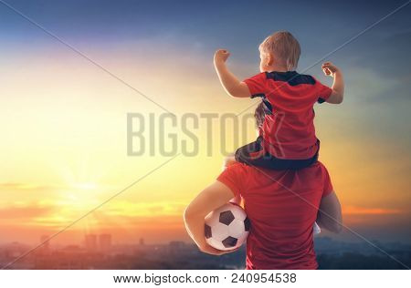 Cute little child dreaming of becoming a soccer player. Boy with man playing football on sunset. Family sport.