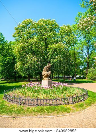 Sculpture Of Seated Woman In Letna Park On Sunny Summer Day With Pitnk Tulips, Prague, Czech Republi