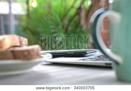 Working On The Computer And Cell Phone While Having Breakfast. Work From Home Or Flexi Time Concept.