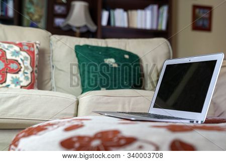 Laptop On A Fabric Top With Couch And Book Shelf On Sight, A Home Environment. Work From Home Of Fle