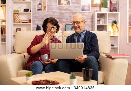 Elderly Old Couple Using Modern Laptop To Chat With Their Grandson
