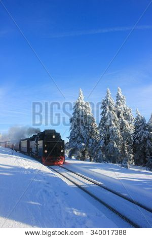 An Old Train Rides On Rails In Winter. Snow-covered Brockenbahn Or Brocken Railway, In Winter, On To