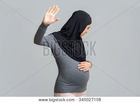 Islam And Domestic Violence Concept. Scared Pregnant Muslim Woman In Hijab Doing Stop Gesture, Hidin