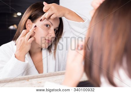 Portrait Of A Beautiful Girl, In The Reflection Of The Mirror. Fingers Remove Acne On The Face.