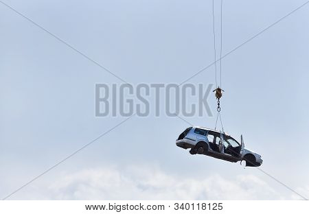 Discarded Old Car Without Wheels, Lifted Up By Cables Against A Sky Before Recycling, With Text Spac