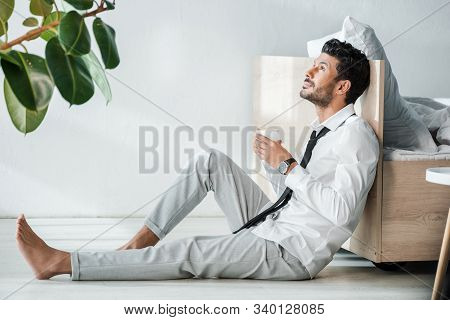 Side View Of Handsome Bi-racial Businessman Holding Cup Of Coffee In Morning