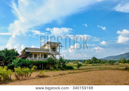 Yellow Wooden House, Decorated With Plants And Flowers, Stands In The Middle Of Farmland, Mountain,