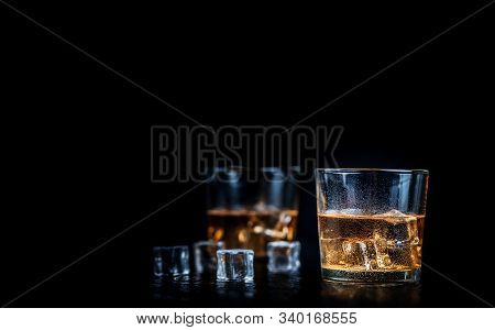 Whisky, Whiskey, Bourbon Or Cognac With Ice Cudes On Black Stone Table