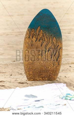 A Close Up View Of A Body, Surf Board In The Sand Next To A Beach Towl On A Warm Summers Day