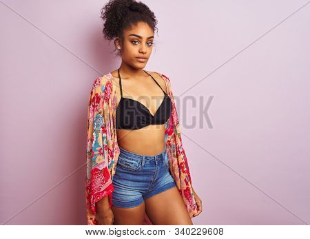Young beautiful african american woman on vacation standing wearing bikini and colorful caftan