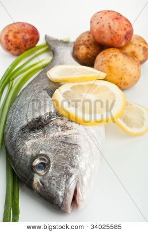 pescado crudo dorado con verduras y limón en primer plano blanco