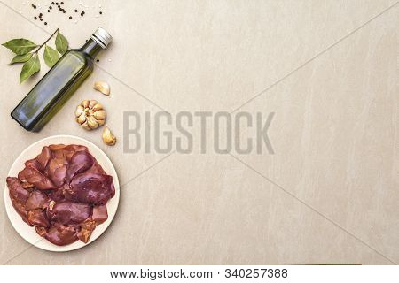 Raw Chicken Liver With Spices On A Stone Background. Garlic, Olive Oil, Black Pepper, Bay Leaf, Top