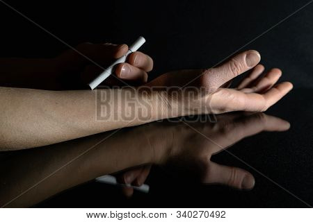 Cigarette In Hand On Black Background With Reflection. The Concept On The Subject Of Health And Smok