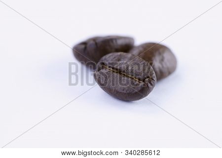 Three Grains Of Coffee On A White Background.close-up, Horizontal, Macro, Place For Text.