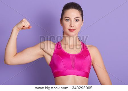 Image Of Strong Confident Fitness Trainer Looking Directly At Camera, Clenching Fist, Showing Muscle
