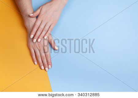 Beautiful Female Hands With A Classic Matte Manicure On A Blue-yellow Background. Place For Your Tex