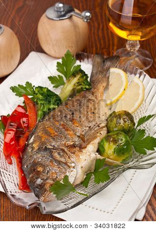 Pez dorado con verduras, hierbas y limón en un plato