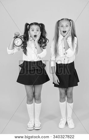 School Time. Surprised Shocked Kids Hold Alarm Clock Counting Time. Latecomer Will Be Punished. It I
