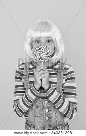 Sweet Tooth. Little Child Hold Lollipop Candy Yellow Background. Small Girl With Rainbow Swirl Candy