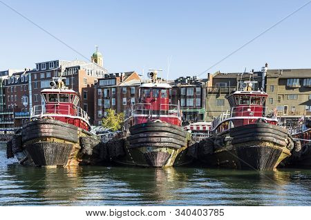 Portsmouth, Usa - Sep 27, 2017:  Tug Boats Anker In Row In Front Of Harbor Building. The Old Harbor 