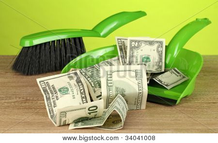 Zametá peníze v lopatu na barevné pozadí detail