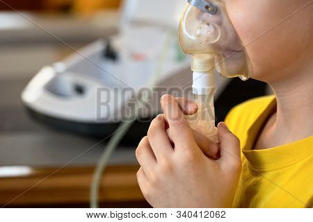 Child Makes Inhalation At Home With Nebulizer On Out Of Focus Background. Example Of Combating Respi