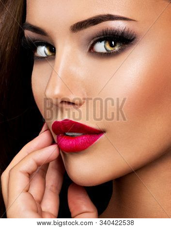 Closeup portrait of beautiful seductive woman with dark brown eye makeup and bright red lips 