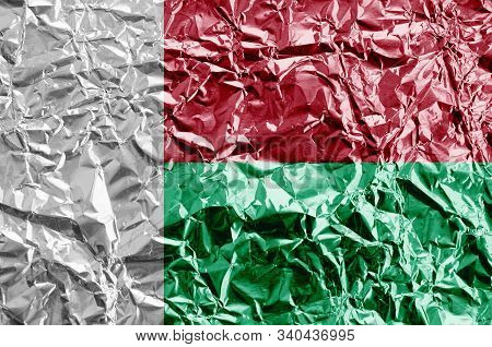 Madagascar Flag Depicted In Paint Colors On Shiny Crumpled Aluminium Foil Closeup. Textured Banner O