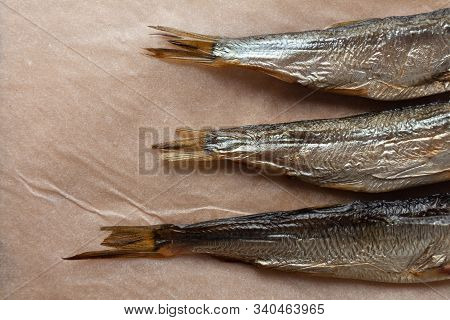 Three Smoked Sea Fish On Parchment Paper. Caught And Cooked Herring. Minimalistic Still Life