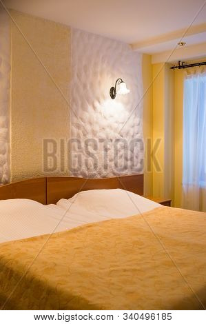 Modern Bedroom Waiting For Couple. Yellow Blanket On Bed In Elegant Bedroom Interior. Wall Lamps Lam
