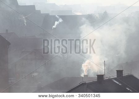 Smoking Chimneys At Roofs Of Houses Emits Smoke, Smog At Sunrise, Pollutants Enter Atmosphere. Envir