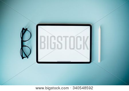Digital Tablet On Blue Background. Flat Lay Style. Clean White Screen For Your Text