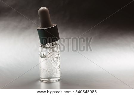 Bottle Of Hyaluronic Acid With Pipette On Silver Background. Front View.