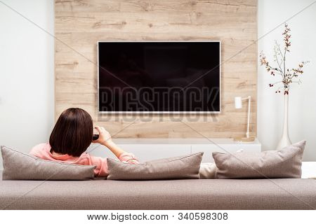 Beautiful Happy Brown-haired Young Female Relaxing With Glass Of Red Wine On The Sofa And Watching T