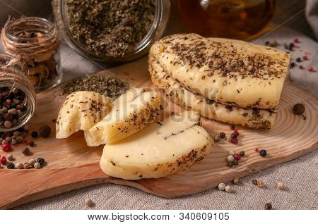 Halumi Cheese With Spices Is Sliced ​​on A Wooden Board. Decorated With Spices. In The Background Gl