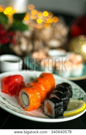 California Rolls And Sushi Poppies On Christmas Table With Ginger And Sticks