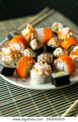 Set Of California Rolls, Butter Cream, Shrimp On A White Platter And A Black Table. With Ginger Soy 