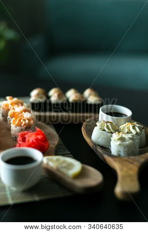 A Set Of California Rolls,some Cream Cheese, Shrimp On Wooden Platters And The Black Table. With Gin