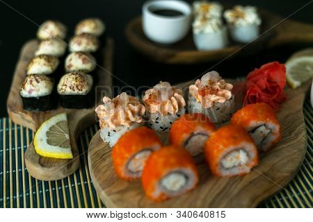 A Set Of California Rolls,some Cream Cheese, Shrimp On Wooden Platters And The Black Table. With Gin
