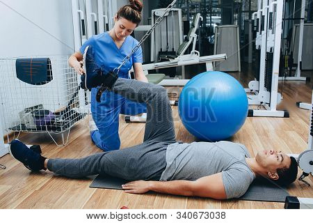 Kinesitherapist Training With A Male Patient Of Mixed Race. The Treatment Of Osteochondritis, Joint 