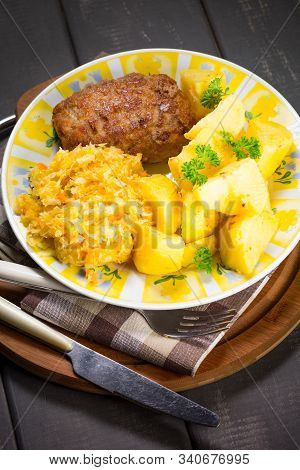 Minced Pork Cutlet Served With Potatoes And Sauerkraut Salad.