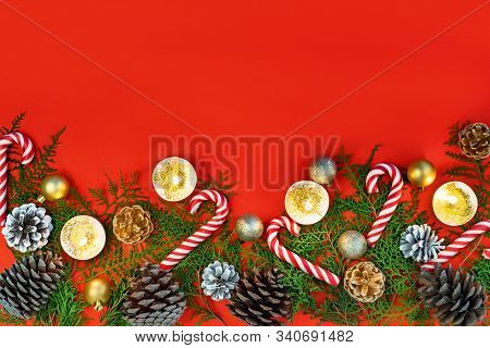 New Year Composition Made Of Christmas Balls, Cones And Striped Hard Candies On Red Background. Flat