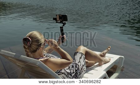 Woman Shooting On Handheld Film Gimbal Stabilization For Smartphone. Girl Lie Sunbed On Pier Make Se