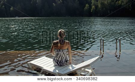 Woman Lie On A Sunbed In Sunglasses And A Boho Silk Shawl. Girl Rest On A Flood Wood Underwater Pier