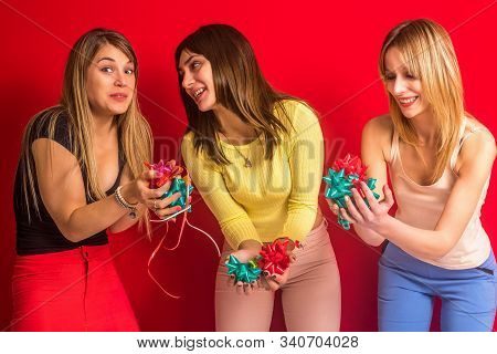 Stock Photo Of Three Girls With Gift Adorns In Their Hands On A Red Background