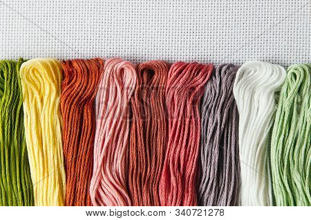 Flat Lay For Needlework And Cross-stitch: Multi-colored Mouline Thread On A White Canvas Aida 16 Cou
