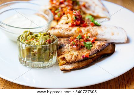 Delicious Mexican quesallidas made with chicken, tomato pieces and served with guacamole sauce.