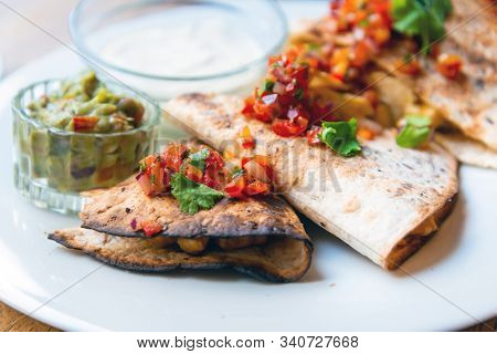 Delicious Mexican quesallidas made with chicken, tomato pieces and served with guacamole sauce.