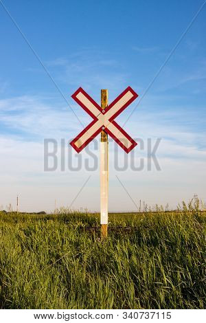 Lone Railroad Crossing Sign On Green Prairie Under Blue Summer Sky