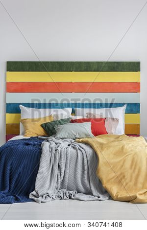 Colorful Bed With Pillows, Blankets And Bedhead With Rainbow Colored Wood